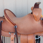 15.5 Trainer full basket weave, latigo wrap, floral conchos, dark straight-back, stirurp leathers on the outside, barbed wire w channels border