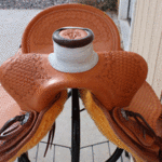 Bronc Buster - 16 in, mule hide, straight-back, full bskt wv, strp lthrs out and tooled, floral conchos, all light leather, Diamond w sswirl border - $2870