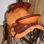 Trainer - 2 strand barbed wire w channels, full basket wv, 2-tone, straight-back, latigo wrap, floral conchos, 2 in bell stirrups, leathers out