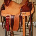 Trainer -2-tone leather,full basket weave,2-strand barbed wire w channels,tooled stirrup lthers, breeching rings,2 inch bell rawhide,stirrup leathers out, straight-back,latigo wrap
