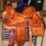 Trainer -corner basket weave,2 strand barbed wire w channels, removeable saddlebags,straight-back,latigo wrap,2 inch bell rawhide stirrups, stirrup leathers out,floral conchos