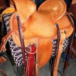 Trainer -sswirl w channels border, straight-back, stirrup lthrs under, brass oxbows, latigo wrap, floral conchos