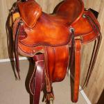 Trainer - latigo, straight-back, floral, oxbows, rope strap, barbed wire w channels, leathers out